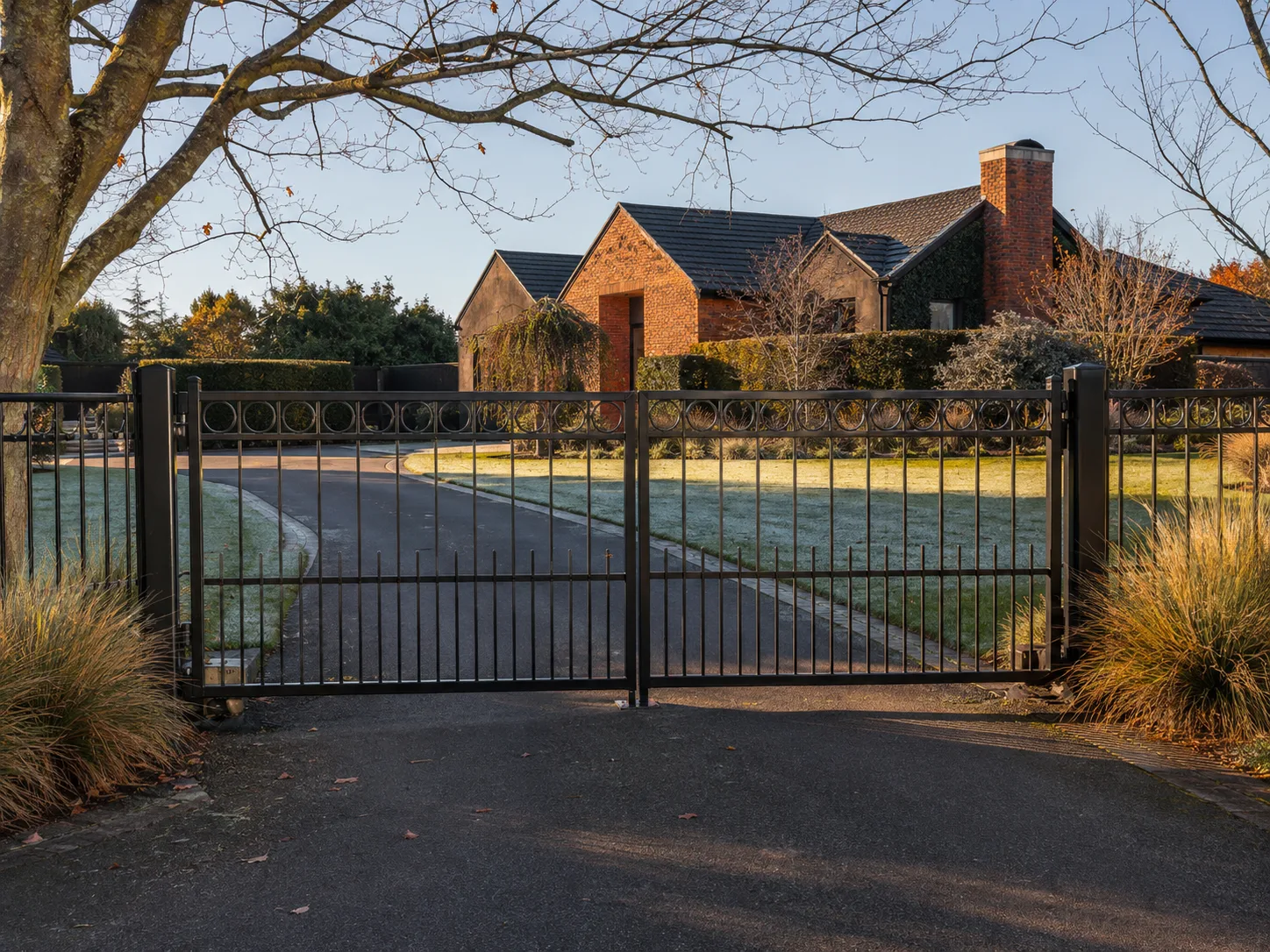 Decorative black double driveway gate outside a brick home