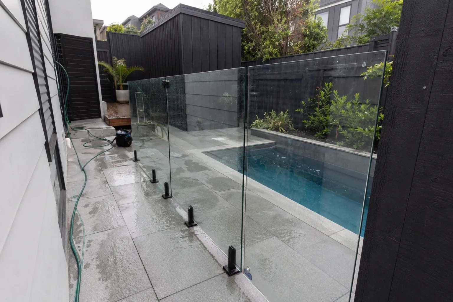 Frameless glass safety fence around a narrow residential pool