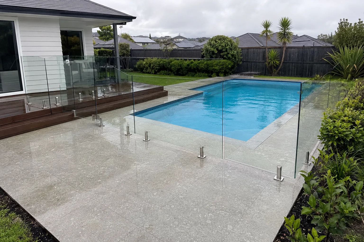 Frameless glass pool barrier enclosing a large paved patio