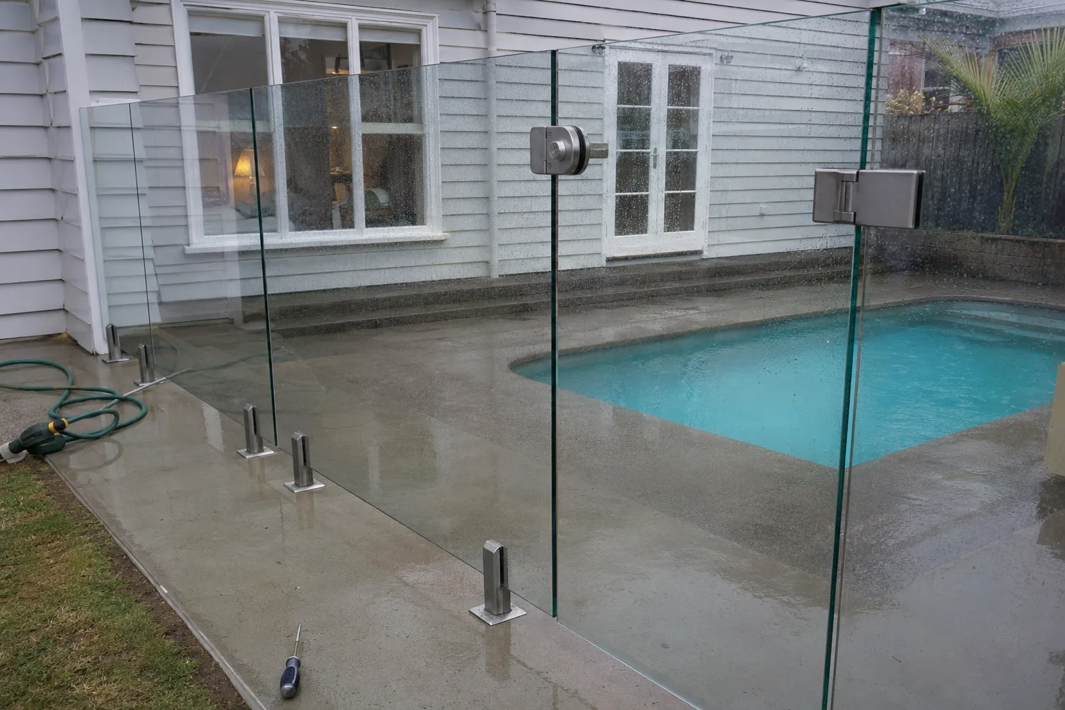 Close view of frameless glass pool gate hinges and latch hardware
