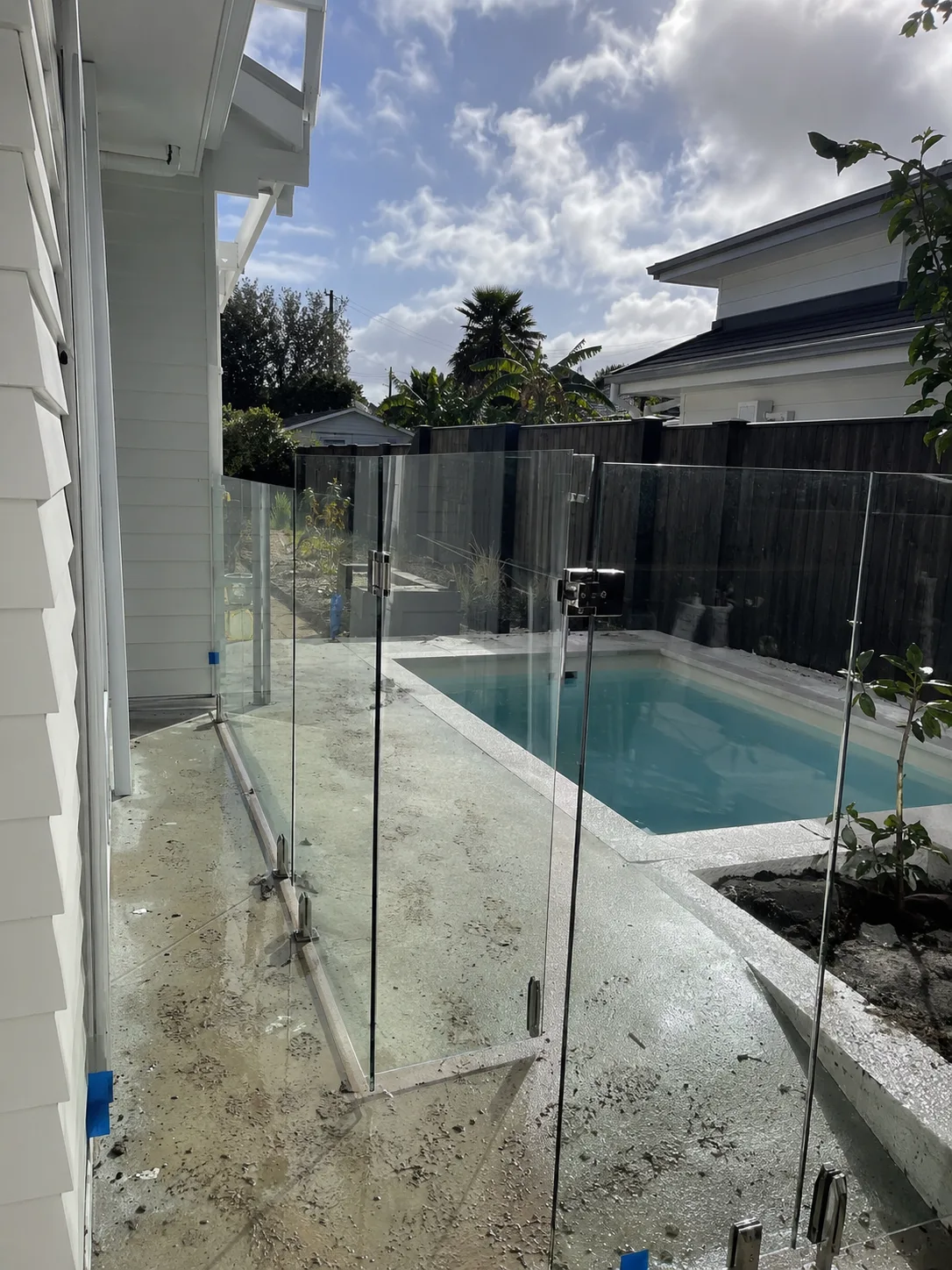 Frameless glass pool gate beside a narrow pool under construction