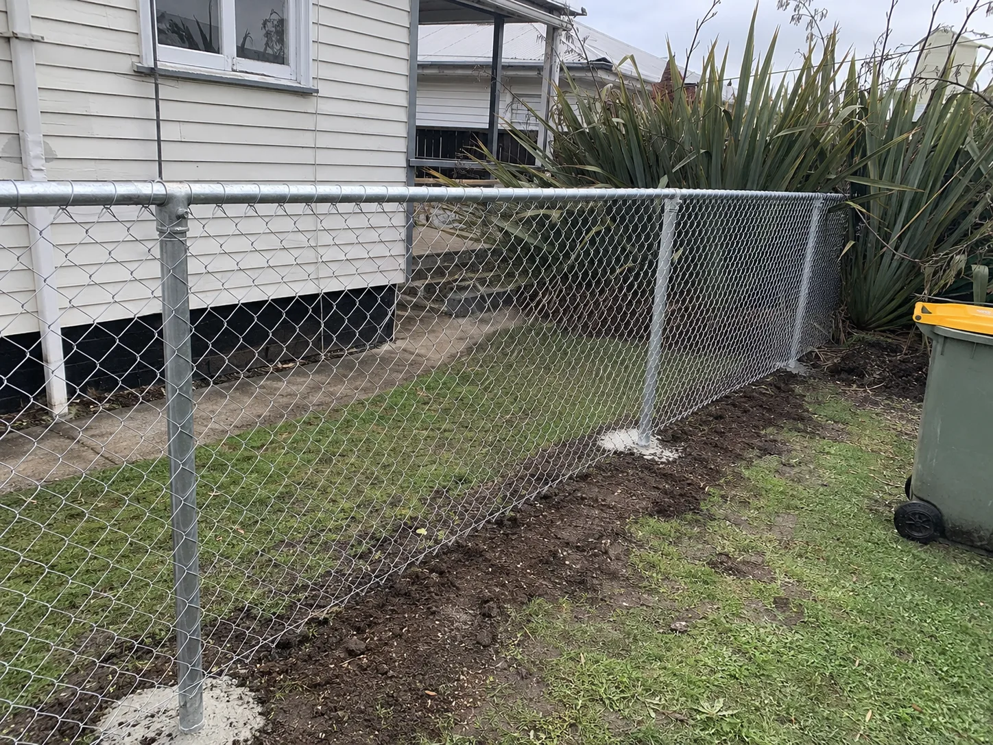 Galvanised chain-link boundary fence around a residential backyard