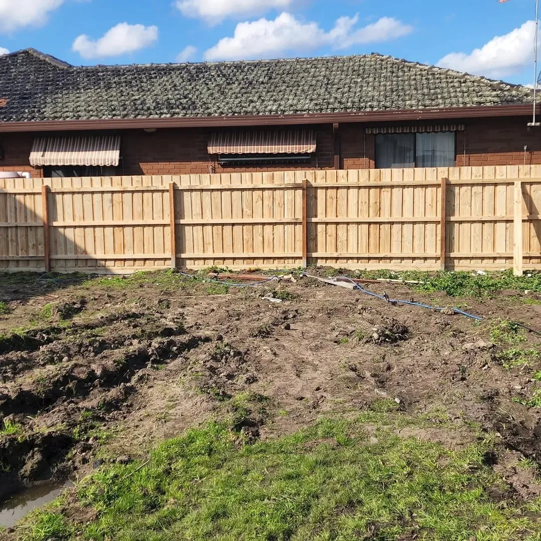 New timber paling fence with rails visible in a muddy residential yard