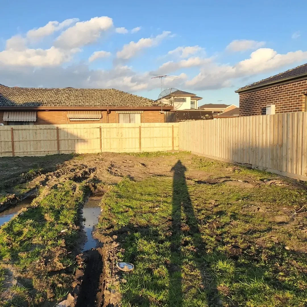 Timber boundary fence around a cleared and muddy residential backyard