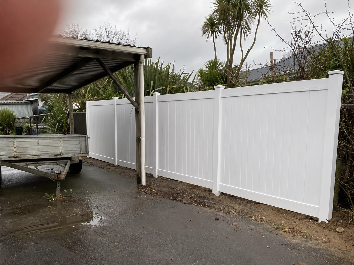 White PVC privacy fence beside a residential driveway and carport